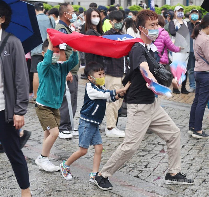 圖為民眾身上披著國旗帶著小孩到台北市國慶升旗暨慶祝活動共襄盛舉，吸引眾人目光。中央社記者張新偉攝 111年10月10日