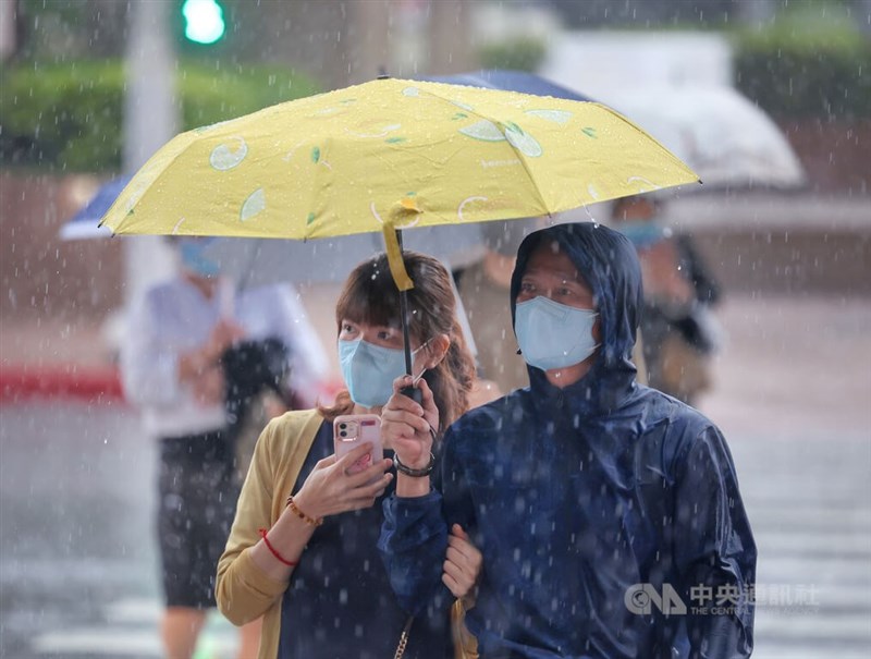 氣象局17日發豪雨特報，颱風外圍環流及東北季風影響，大台北山區、基隆北海岸防豪雨。圖為台北市中正區民眾撐傘過馬路。（中央社檔案照片）