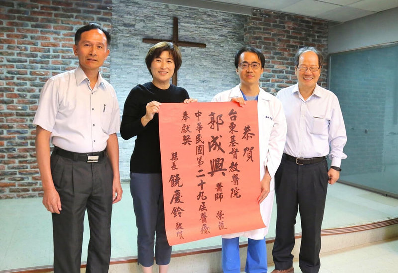 高雄醫學大學學士後醫學系校友郭成興(右2)毅然從繁華故鄉台北市遠赴台東服務,2019年榮獲第29屆「醫療奉獻獎」,台東縣長饒慶鈴(左2)貼紅榜祝賀。(高醫提供)中央社記者曾以寧傳真 111年10月17日