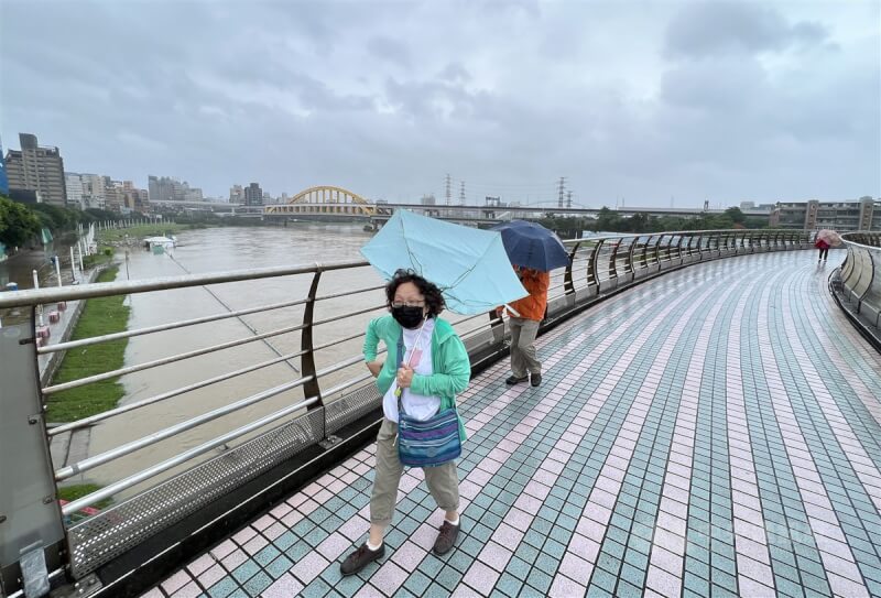 中央氣象局表示，18日起至19日降雨漸緩，北部、東北部仍要留意較大雨勢。圖為民眾到台北市松山區彩虹橋，雨傘被強風吹翻。中央社記者鄭傑文攝 111年10月17日