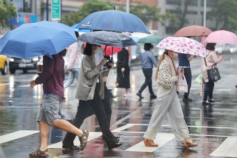 氣象專家吳德榮表示，18日迎風面水氣仍多，北台灣濕冷、中南部晴時多雲。圖為走在台北市內湖科技園區街頭的民眾中午撐傘遮雨。（中央社檔案照片）