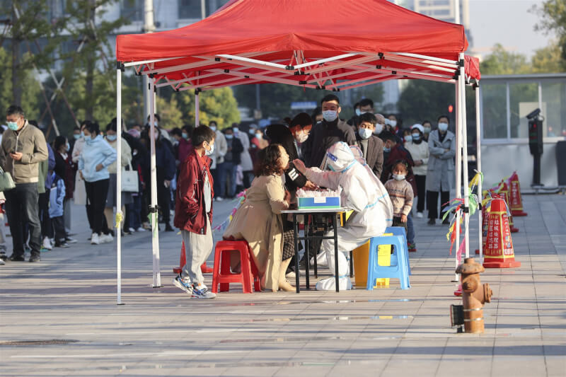 中國各地持續推進動態清零，核酸檢疫也不斷升級，繼3天2檢、1天1檢後，鄭州及廣州要求1天2檢。圖為19日江蘇省連雲市青口鎮當地居民等候核酸檢測。（中新社）