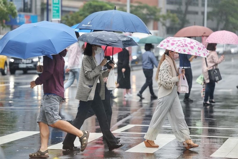 中央氣象局表示，23日桃園以北、東半部地區及中南部山區降雨機率高。圖為走在台北市內湖科技園區街頭的民眾撐傘遮雨。（中央社檔案照片）