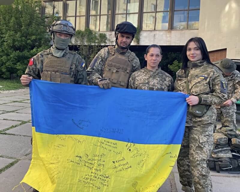 曾加入烏克蘭國際志願軍的呂子豪（左1）23日表示，對烏克蘭政府有幫助的人，都會收到一面烏克蘭國旗，他也請隊友在上面簽名留念。（呂子豪提供）中央社記者陳俊華傳真 111年10月23日