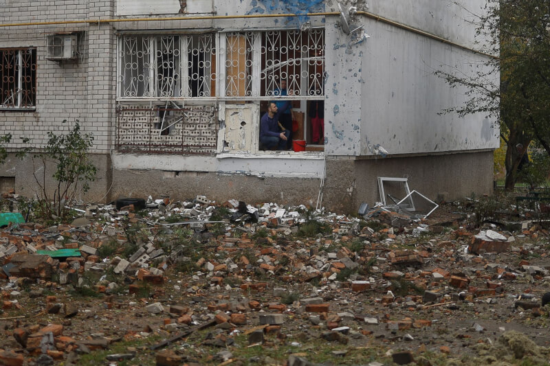 圖為23日尼古拉耶夫居民檢查被俄軍導彈擊毀的公寓陽台。（路透社）