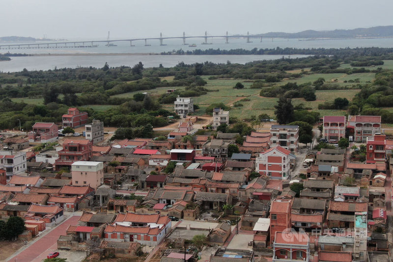 金門大橋(後)西起烈嶼后頭地區、東迄於金寧鄉慈湖地區,路線全長約5.4公里,其中約4.77公里位於海上,日前已辦理大橋通車前履勘,相關改善事項可於28日完成,預計30日開放通車。圖前為111年10月19日金門縣金寧鄉南山聚落,古厝成群。中央社記者徐肇昌攝 111年10月26日