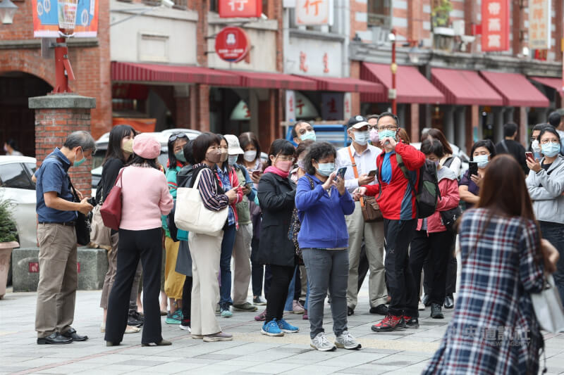 圖為民眾戴著口罩到台北迪化街，在導覽員解說下，瞭解商圈歷史。（中央社檔案照片）