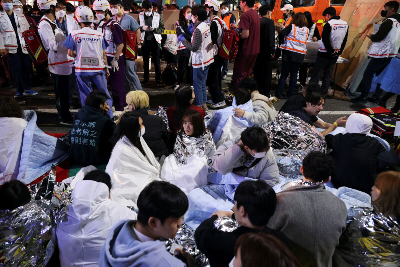 韓國首爾梨泰院29日萬聖節活動釀推擠踩踏百死事故，部份參與活動的民眾被救出後暫坐路旁休息。（路透社）