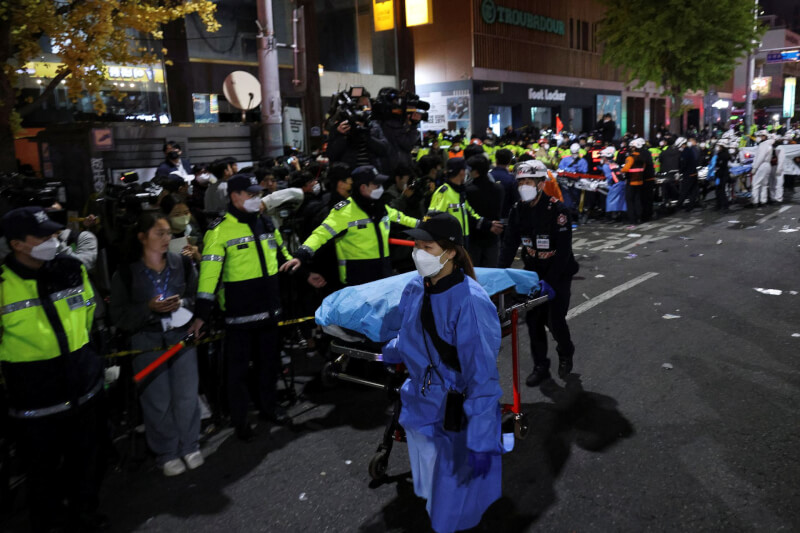 韓國梨泰院的萬聖節狂歡人潮，造成逾百死踩踏意外，大批警力29日晚間在現場維護秩序，相關人員協助受害者遺體送至醫院。（路透社）