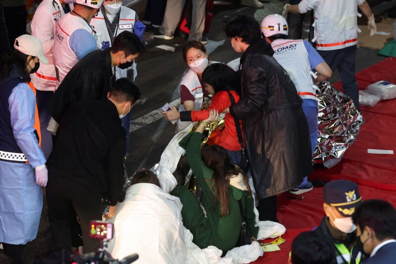 圖為29日晚間韓國梨泰院踩踏事故現場人員協助救援受害者。（路透社）