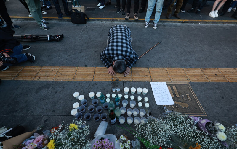 韓國梨泰院29日踩踏意外，至今已153人不治，103人受傷送醫治療。圖為一名市民在梨泰院站出口旁下跪致哀。（韓聯社）
