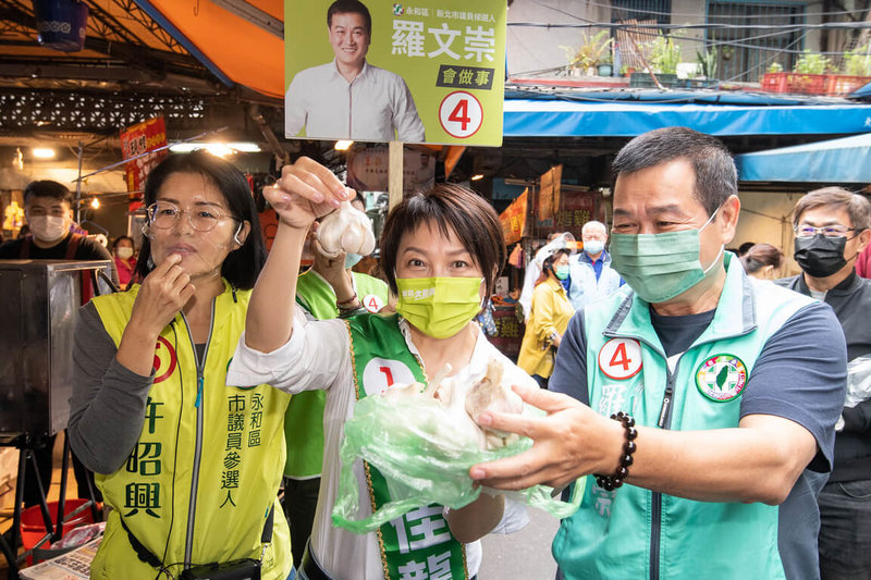 民進黨立委范雲（前中）1日披上同黨新北市長參選人林佳龍的競選背帶到永和區市場掃街拜票，為新北選情拉抬造勢，獲民眾送上有「凍蒜」寓意的蒜頭祝福。（林佳龍競選辦公室提供）中央社記者黃旭昇新北市傳真  111年11月1日