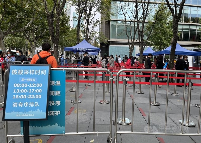 中國多地11月起將常態化核酸檢測改為付費制。圖為10月30日上海街頭核酸檢測採樣亭和排隊等待受檢的民眾。（中央社檔案照片）