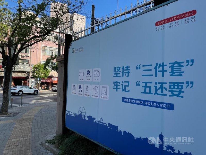 在COVID-19動態清零方針下，上海市推動常態化防疫措施，圖為街口防疫宣傳看板。「三件套」所指的是，佩戴口罩、保持社交距離、注意個人衛生；「五還要」則是口罩還要戴、社交距離還要留、咳嗽噴嚏還要遮、雙手還要經常洗、窗戶還要盡量開。中央社記者李雅雯上海攝 111年11月16日