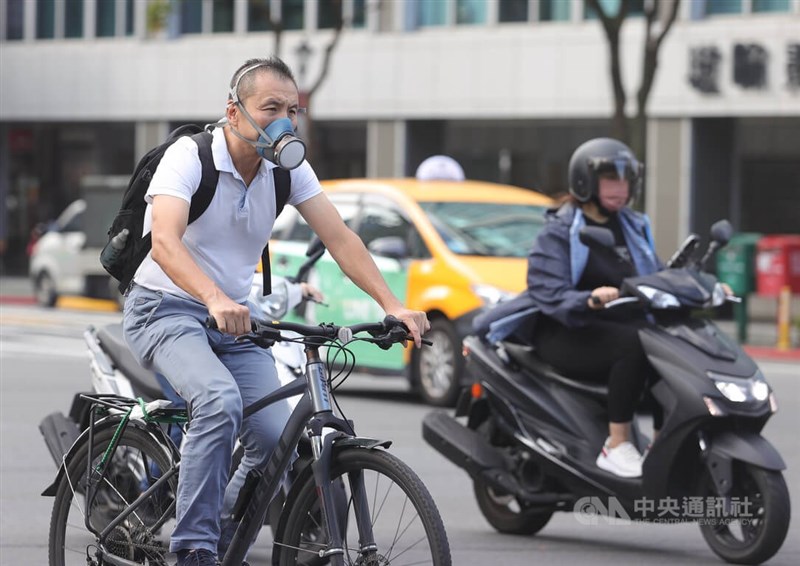 圖為14日有民眾戴著防毒面罩騎自行車行經台北市新生南路一段，防疫不鬆懈。（中央社檔案照片）