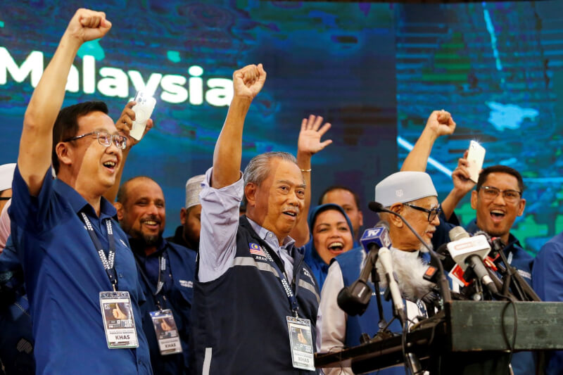 馬來西亞國會大選結果出爐，沒有任何一個政黨席次過半，前首相慕尤丁（前左2）說，已獲其他政黨同意合組政府。圖為慕尤丁20日和其他人一起舉手高喊口號。（路透社）