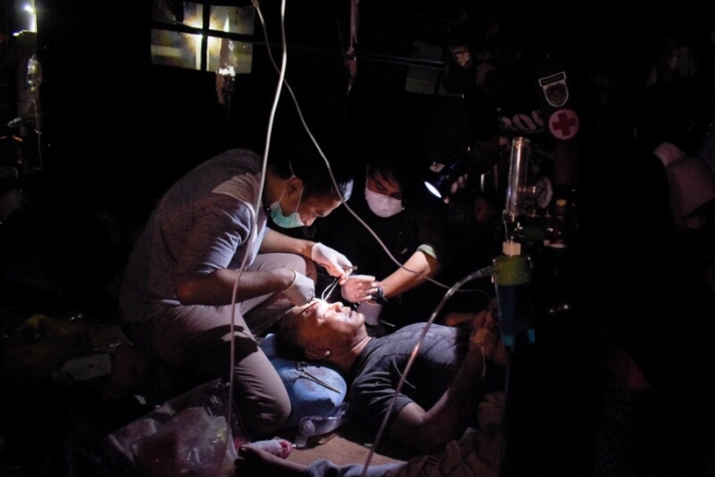 當地因地震無電可用，醫護在手電筒光源下治療災民。（法新社）