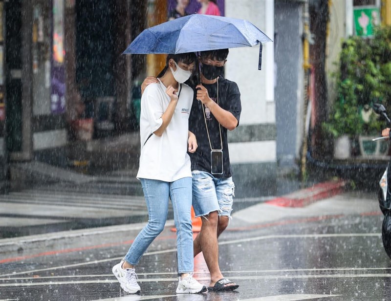 中央氣象局表示，23日至25日天氣轉濕涼，中部以北24、25日可能有較大雨勢。圖為台北市文山區民眾過街共撐一把傘避雨。（中央社檔案照片）