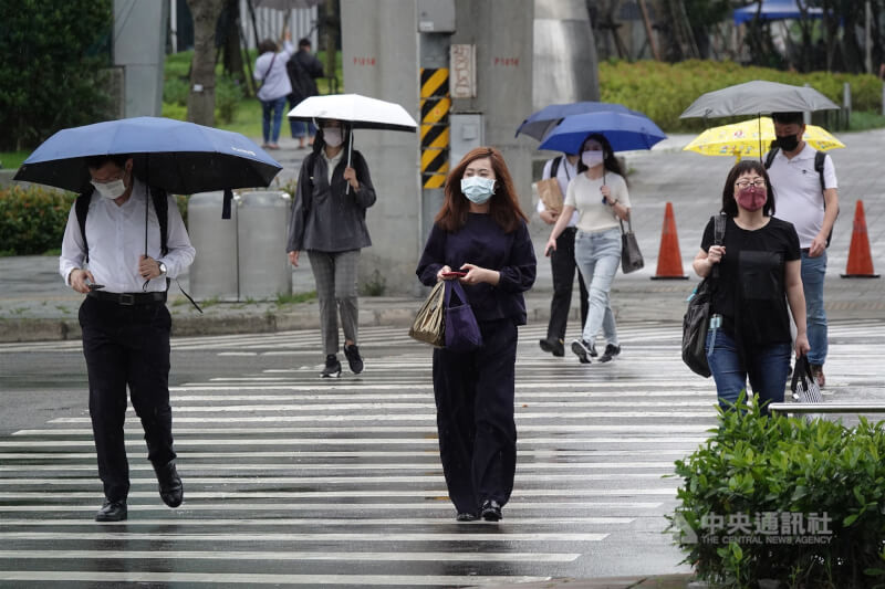 氣象專家吳德榮表示，24至26日清晨各地降雨時大時小。圖為南港軟體園區民眾撐傘過馬路。（中央社檔案照片）