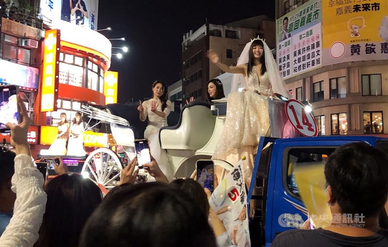 嘉義市傳統的「選前之夜」造勢遊行25日晚間登場,無黨籍市議員候選人「顏色不分藍綠支持性專區顏色田慎節」(車上右)穿上婚紗造勢,成功吸引目光。中央社記者黃國芳攝 111年11月25日