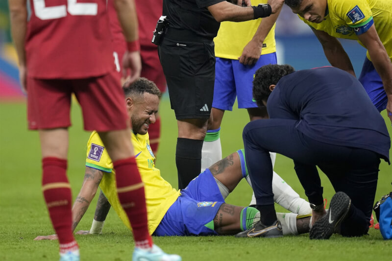 內馬爾（坐姿黃衣者）在巴西與塞爾維亞24日比賽中扭傷腳踝，場內醫護人員替他查看傷勢。（美聯社）