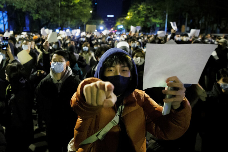 中國反封控抗議潮蔓延至多個省市，掀起象徵示威的白紙運動。圖為27日北京大批民眾在街頭舉白紙示威。（路透社）