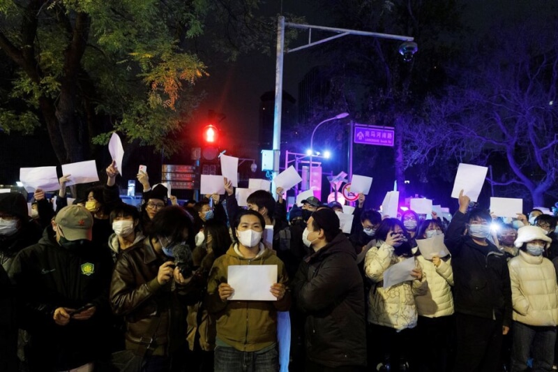 北京民眾27日晚間聚集在亮馬河周圍，手舉白紙抗議中國防疫政策。（路透社）