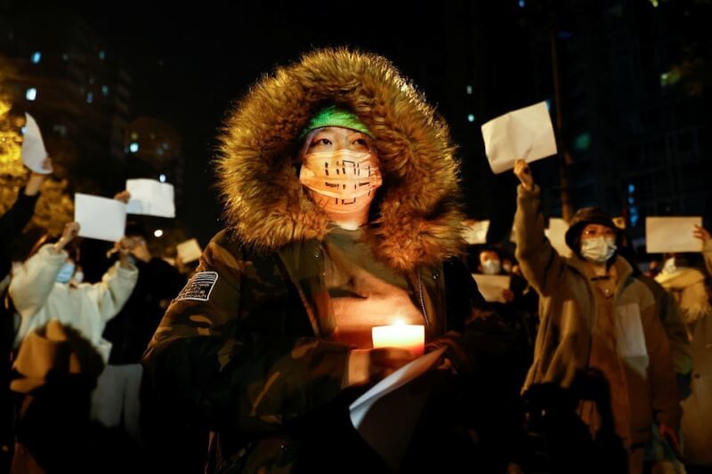 中國北京民眾27日晚間舉起白紙抗議中國防疫政策，並在為新疆烏魯木齊火災罹難者舉行的守夜活動點亮蠟燭。（路透社）