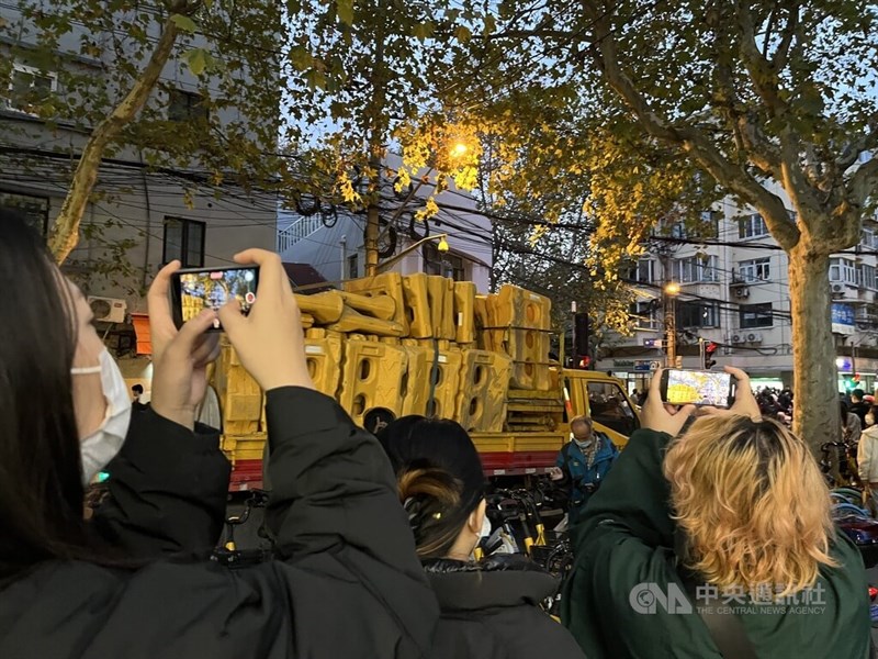 上海警方27日將路障放置烏魯木齊中路、五原路交叉口，禁止人流往北段走；現場民眾拿起手機記錄現場情形。中央社記者李雅雯上海攝 111年11月27日