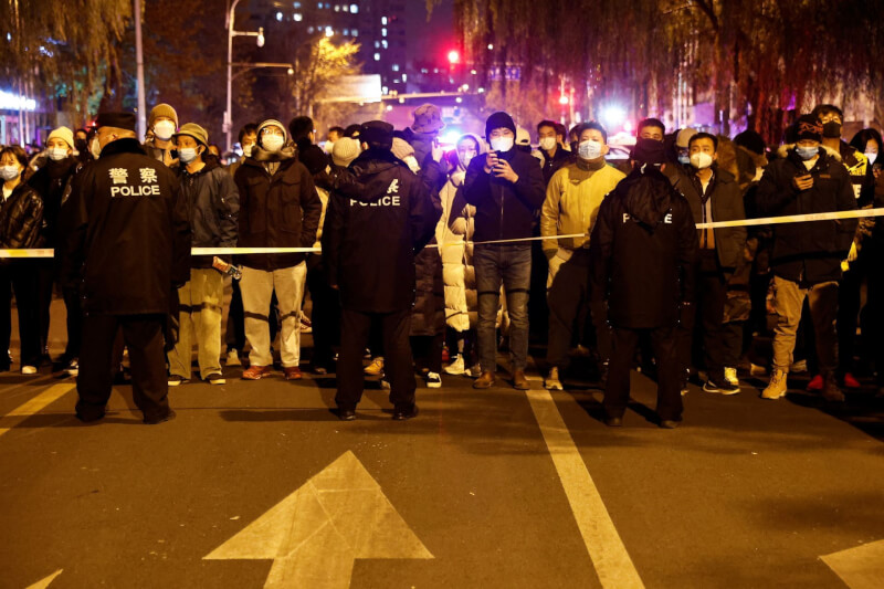 圖為去年11月27日，中國民眾在北京街頭手舉白紙抗議防疫政策。（路透社）
