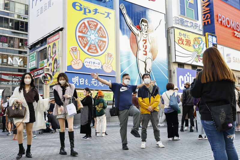 圖為11日11日大阪遊客和格力高跑跑人看板合照。（共同社）