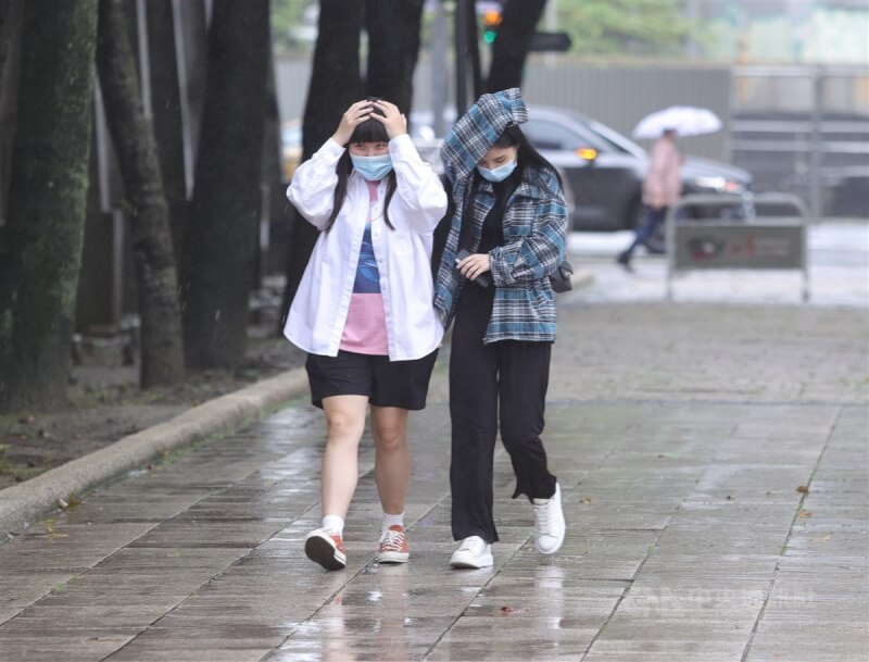 中央氣象局2日針對基隆北海岸、台北市山區、新北市、宜蘭縣4縣市發布大雨特報。圖為民眾用手擋雨前進。（中央社檔案照片）