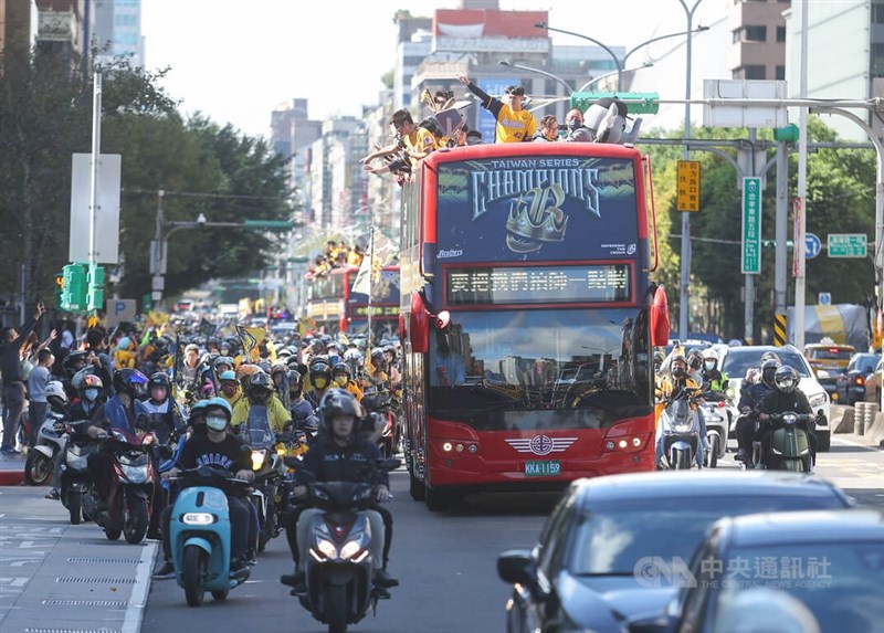 球員在雙層巴士上向支持粉絲致意，許多球迷更是騎車一路跟隨車隊，氣勢壯觀。中央社記者張新偉攝 111年12月3日