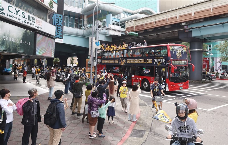 許多球迷騎車一路跟隨車隊前進南港，行經東區忠孝復興路口時，人行道上民眾也向車隊揮手致意。中央社記者張新偉攝　111年12月3日