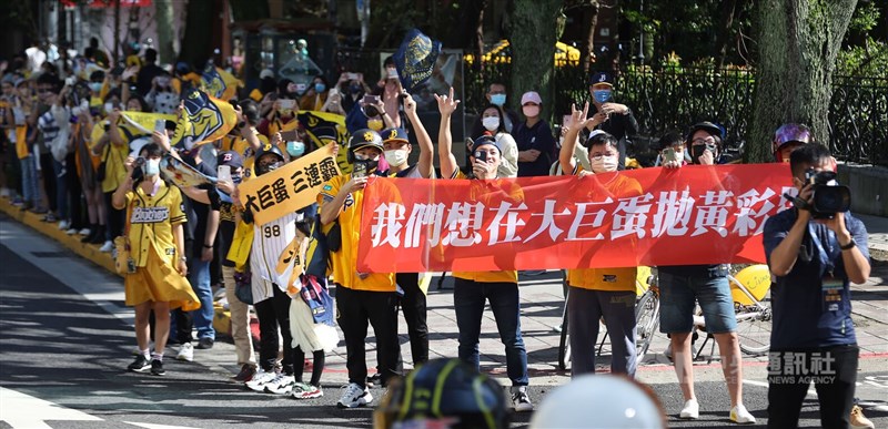 大批球迷穿起黃色球衣到場參與，有球迷還在路邊高舉寫有「我們想在大巨蛋拋黃彩帶」的布條。中央社記者張新偉攝 111年12月3日