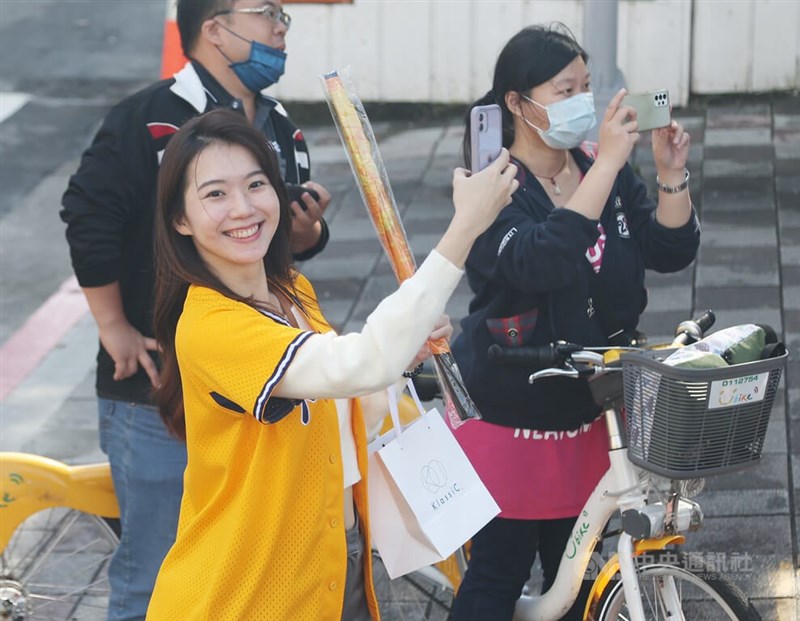 圖為球迷開心穿起黃色球衣等待車隊經過。中央社記者張新偉攝 111年12月3日