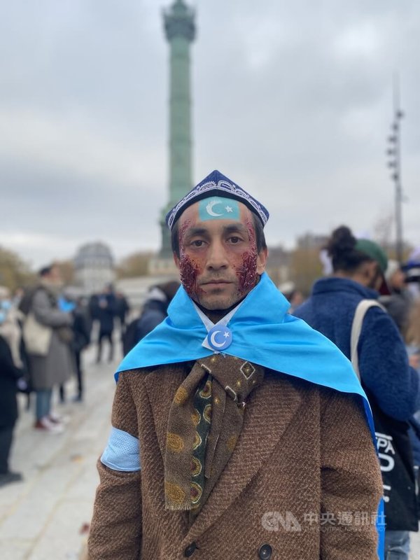 維吾爾族詩人穆丹臉上的傷疤妝代表同胞的苦痛犧牲，他在3日的遊行中強調，若白紙運動只是為了吃上飯的話，就不能稱為運動；真正的民主運動，應是要推翻中共的邪惡統治。中央社記者曾婷瑄巴黎攝 111年12月4日