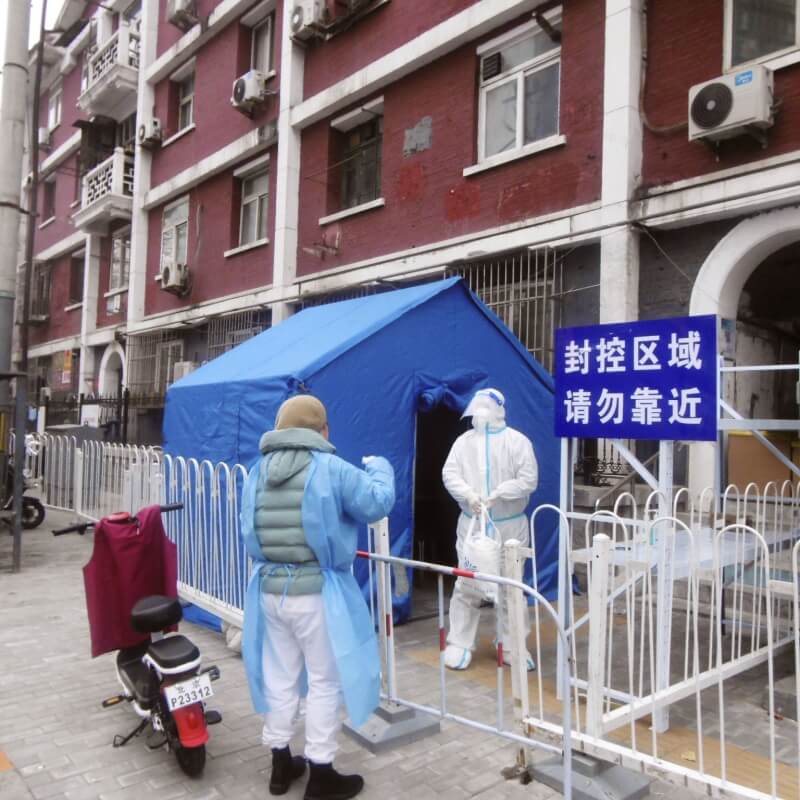 圖為11月24日中國北京看守封控區域的防疫人員。（共同社）