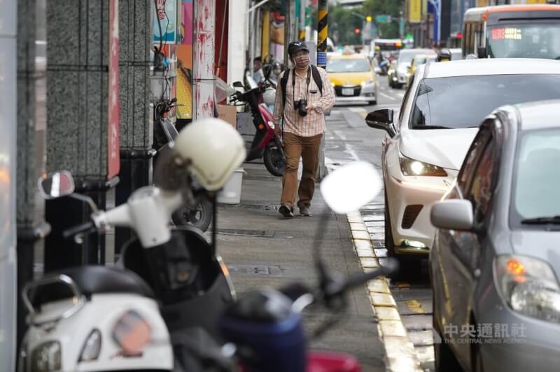 台灣交通遭批評為「行人地獄」，交通部長王國材3日表示，將加強清除人行道和騎樓被占用的部分。圖為一名遊客穿過重重停在人行道的機車，走在台北民生西路大稻埕一帶街頭。（中央社檔案照片）