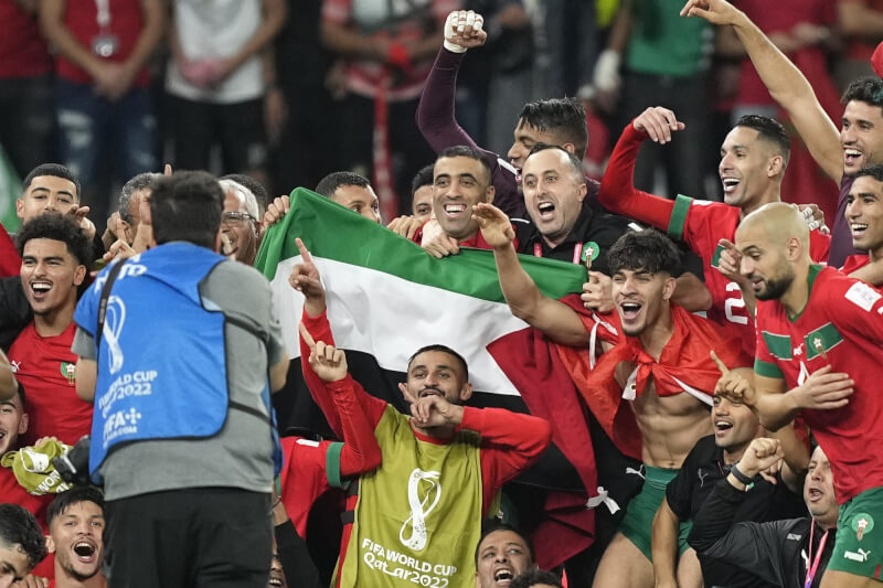 摩洛哥6日在中東地區首次舉辦的世界盃足球賽力克西班牙晉級8強，贏得勝利的摩洛哥隊員賽後公開跟巴勒斯坦旗幟合照。（美聯社）