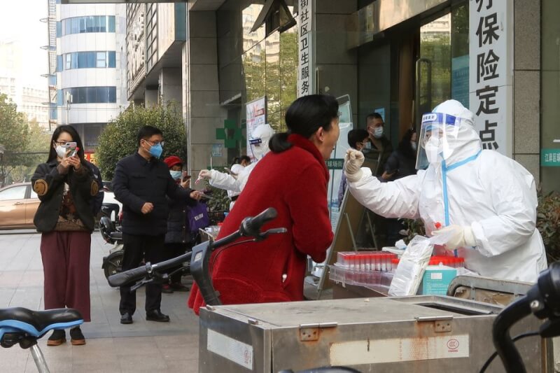 中國工程院院士鍾南山研判，疫情峰值會出現明年1至2月，上半年能恢復到疫情前的生活狀態。圖為9日武漢民眾在路邊做核酸檢測。（路透社）