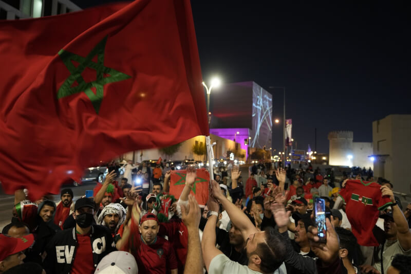 摩洛哥在卡達世界盃足球賽以1比0擊退葡萄牙，成為史上第一支闖進世足4強的非洲和阿拉伯球隊。圖為球迷持摩洛哥國旗歡呼。（美聯社）