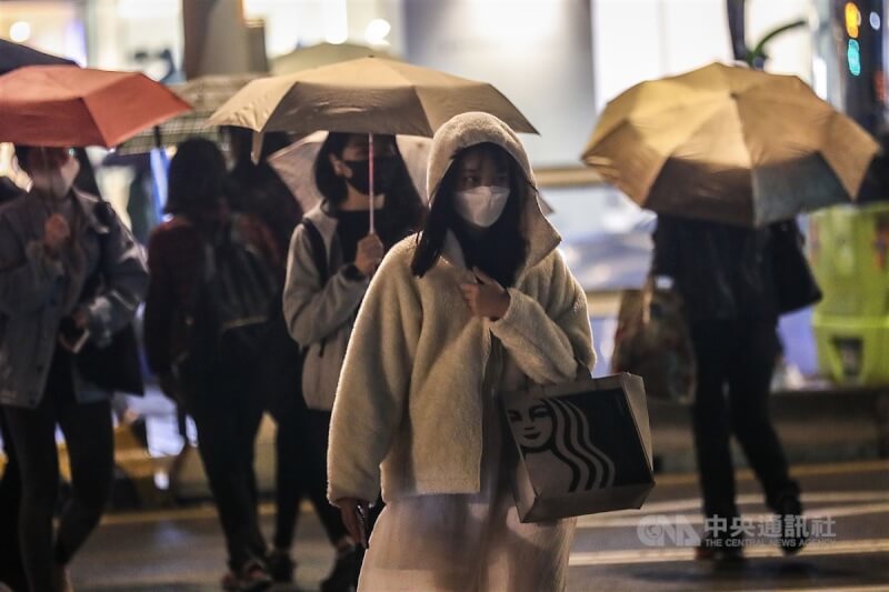 中央氣象局表示，13日白天北部及東北部持續濕冷，預測高溫只有攝氏17至19度。圖為台北市民眾拉緊衣領穿越馬路。（中央社檔案照片）