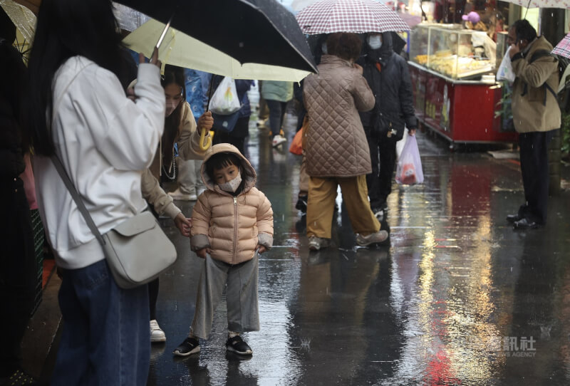 氣象專家吳德榮13日表示，16日晚間首波寒流南下，週末台北氣象站預估將降溫至攝氏9度以下。圖為八里老街逛街的小朋友拎起褲子怕淋濕。（中央社檔案照片）
