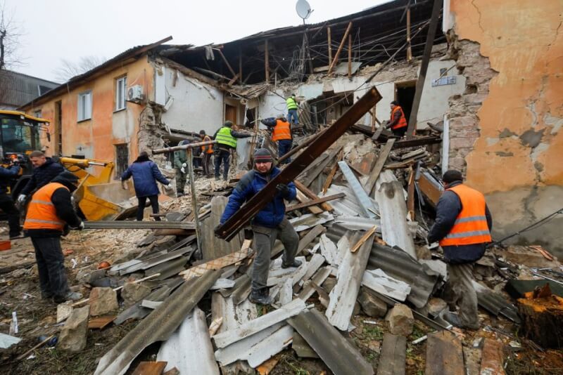 烏克蘭東部的頓內茨克俄占領區居民13日在瓦礫堆中，搬移因轟炸受損的房屋建築。（路透社）