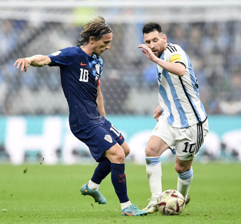 阿根廷球星梅西（右）14日率隊挺進世足冠軍戰，賽後宣告這是他最後一次參加世界盃。圖為梅西和克羅埃西亞球員莫德里奇（左）爭球。（共同社）