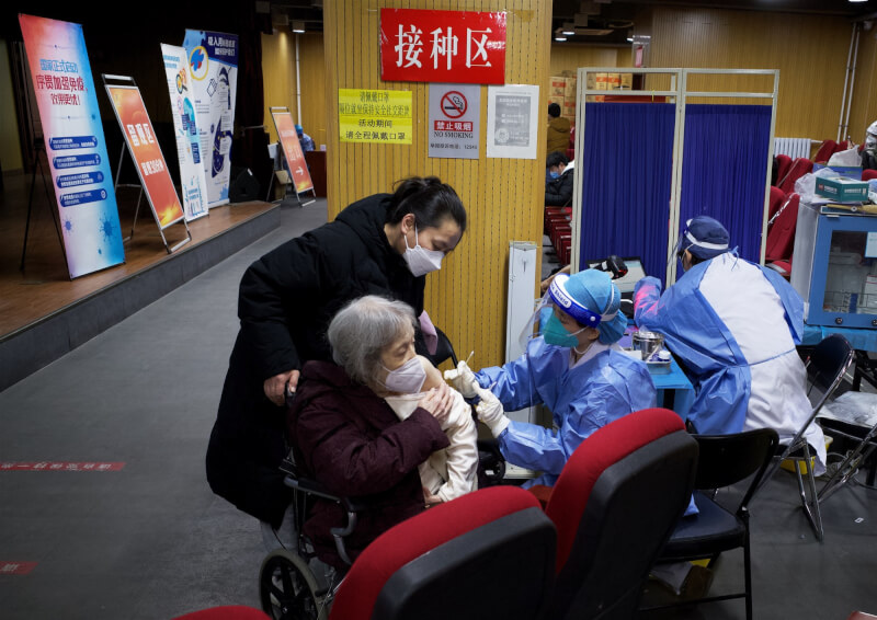 中國感染人數大增，壓迫醫療資源。不少染疫的醫療人員不得不在剛復原後就立即回到工作崗位，更有一些輕症者必須「帶病上工」。圖為北京醫護人員為長者接種疫苗。（中新社）