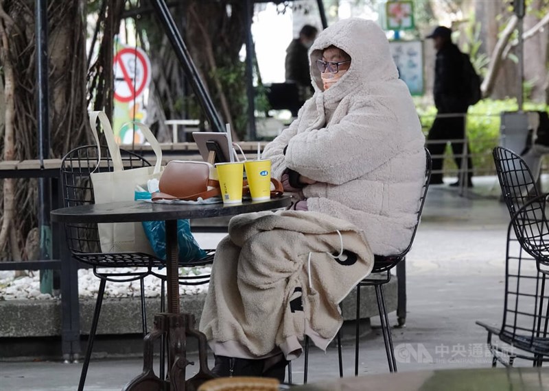 圖為民眾在台北花博公園裹著大衣喝飲料。中央社記者鄭傑文攝 111年12月18日