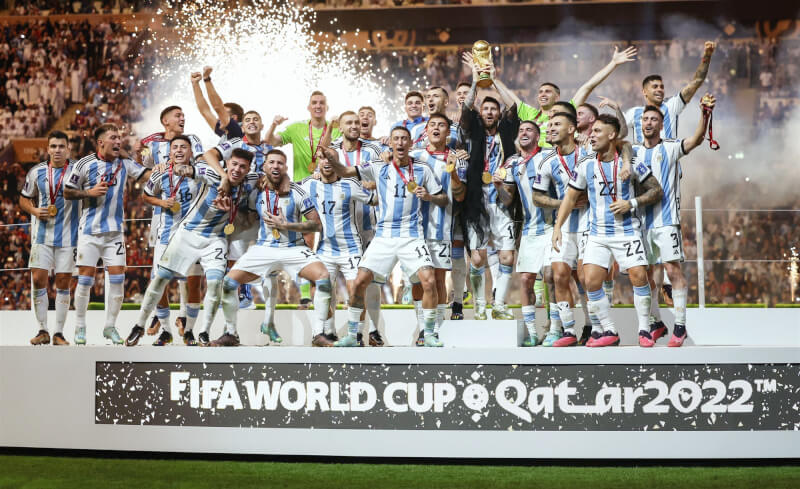 阿根廷在卡達世足決賽擊敗法國，抱回世界盃隊史第3冠，隊長梅西興奮高舉金盃，全隊開心歡呼。（共同社）