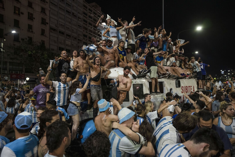 阿根廷民眾18日晚間聚集在布宜諾斯艾利斯街頭慶祝，許多男性脫去上衣高歌，還有情侶在歡呼群眾中親吻彼此。（美聯社）